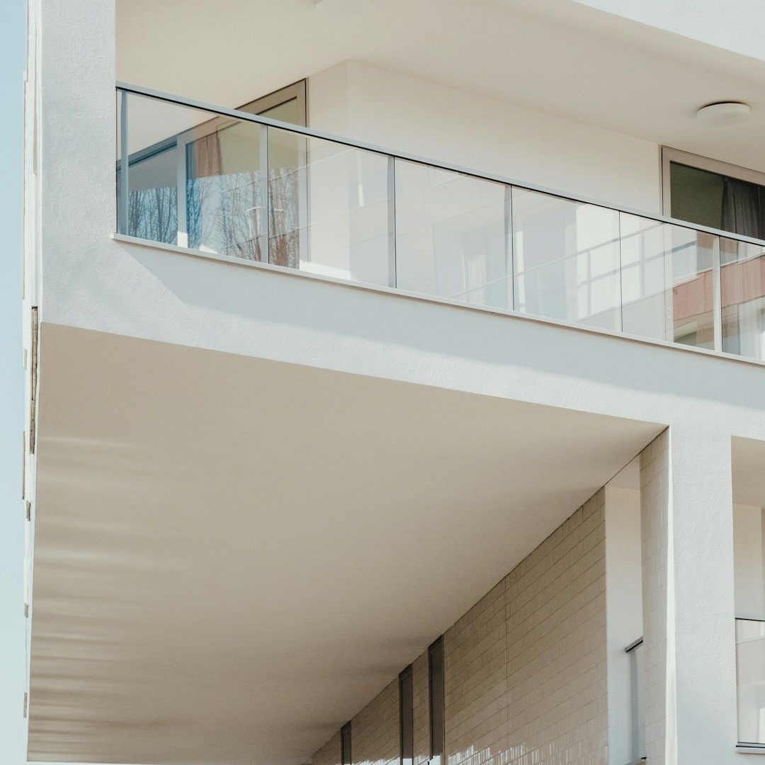 Moderner Wohnbau mit Balkon und großen Fenstern, helle Fassade.